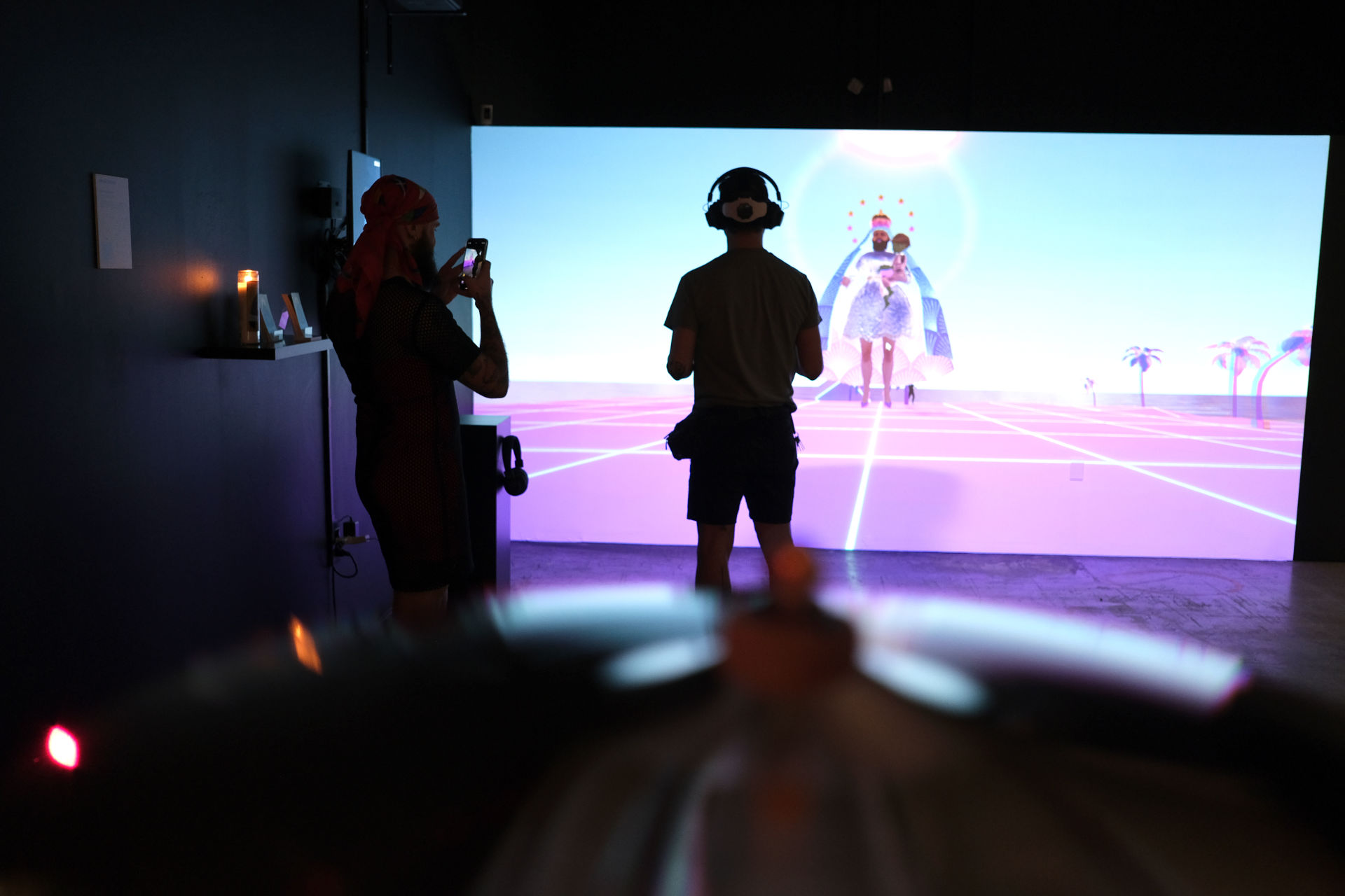 A man standing in from of a screen showing the dragvatar metaverse scene