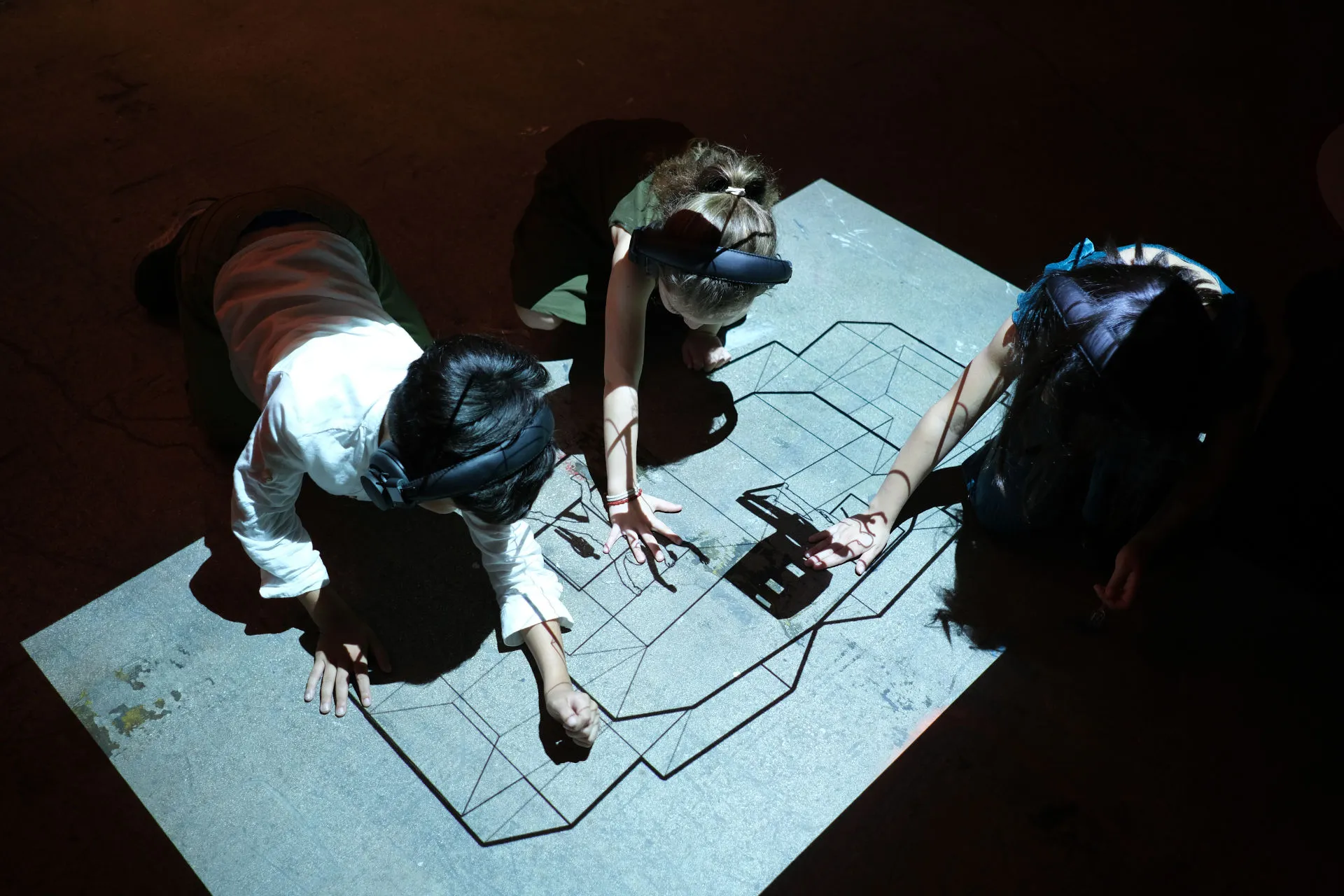 Kids touching the floor and playing over the projection of the New Extractivism piece