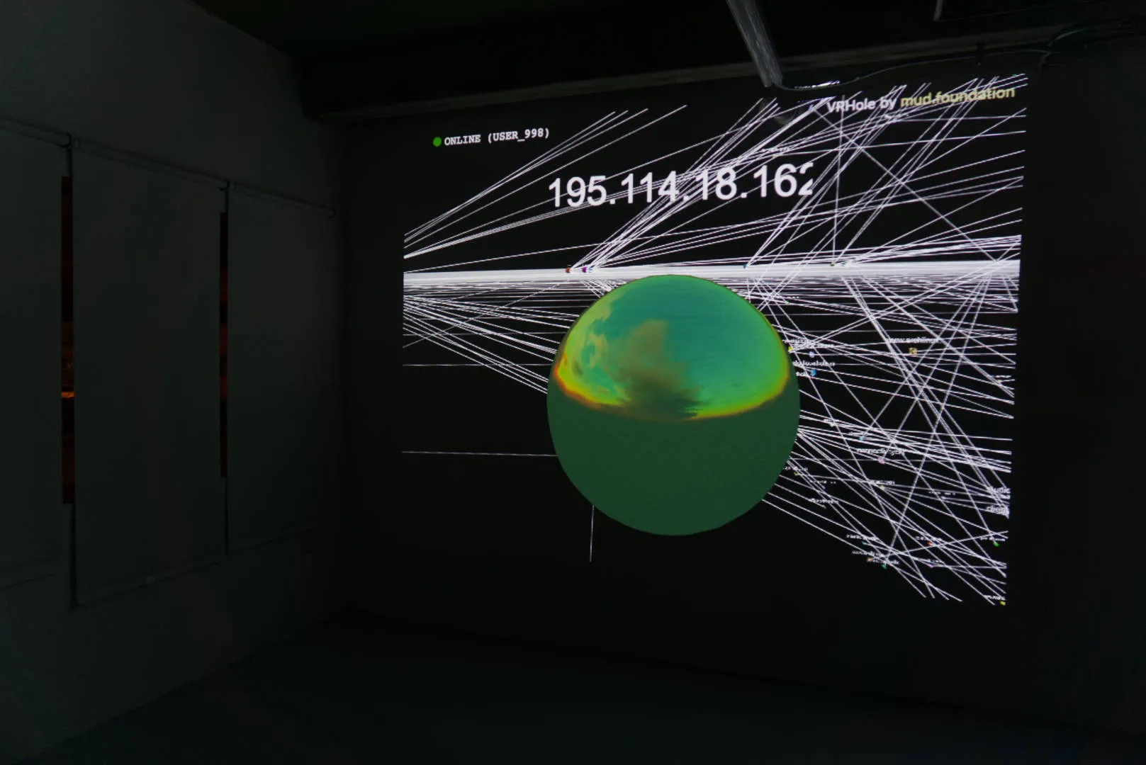 A screen in a dark room showing a green ball, numbers and white lines that intertwines