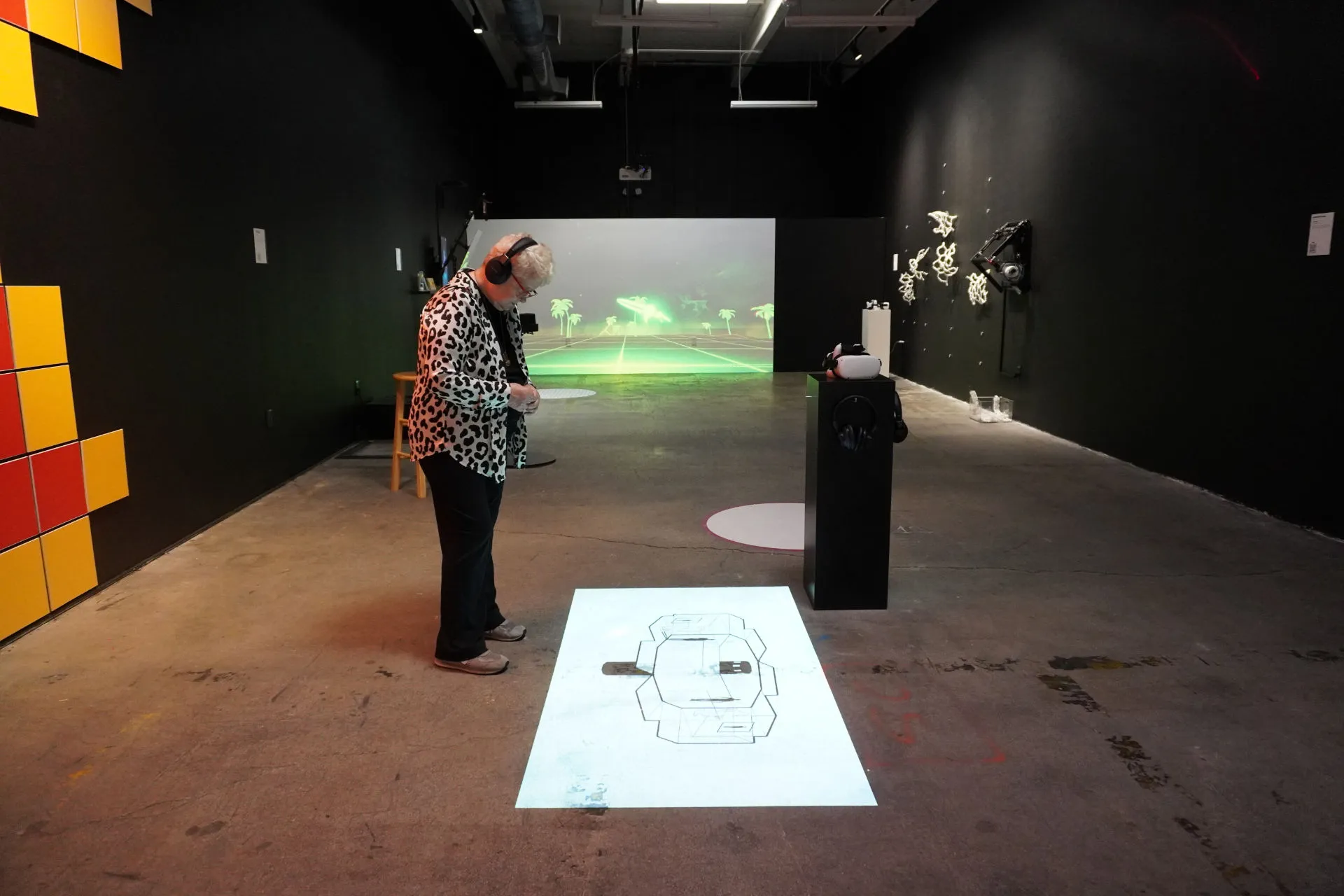 A person with headphones standing in front of a projection of the New Extractivism piece