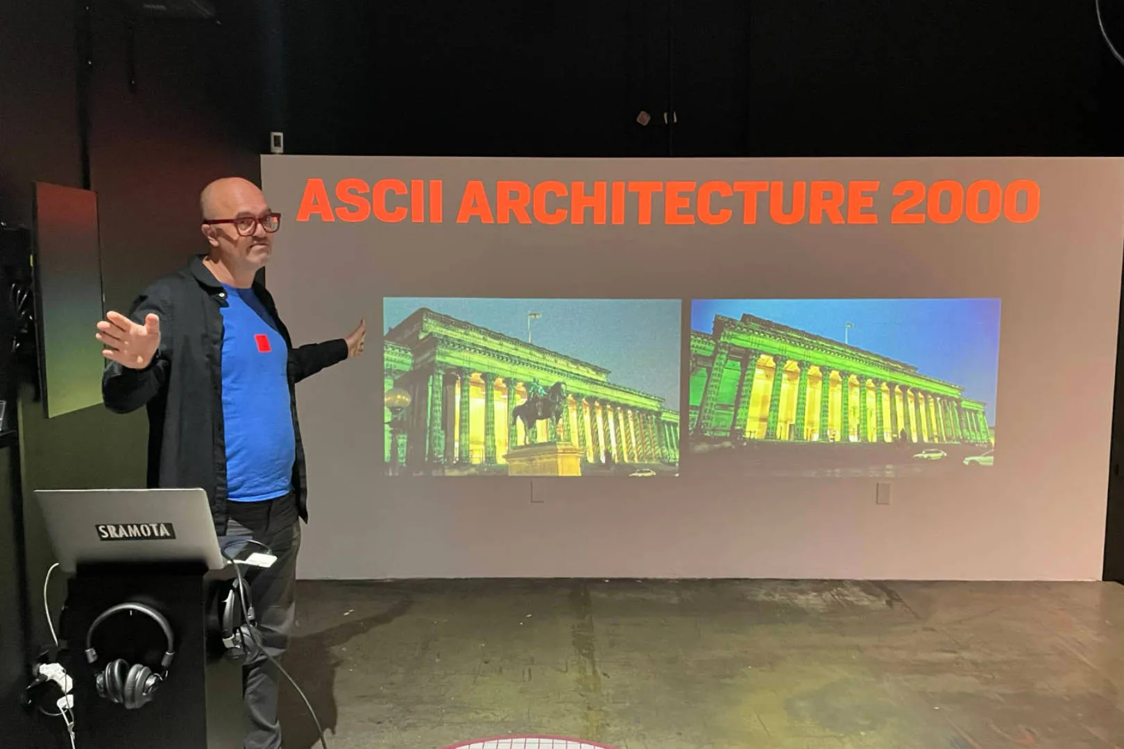 A man standing in front of a screen, doing a presentation on ASCII Architecture