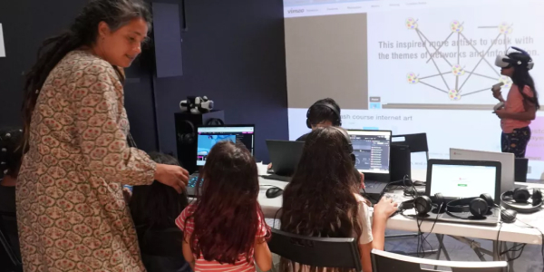A teacher with children in front of computers at the xrcamp educational program