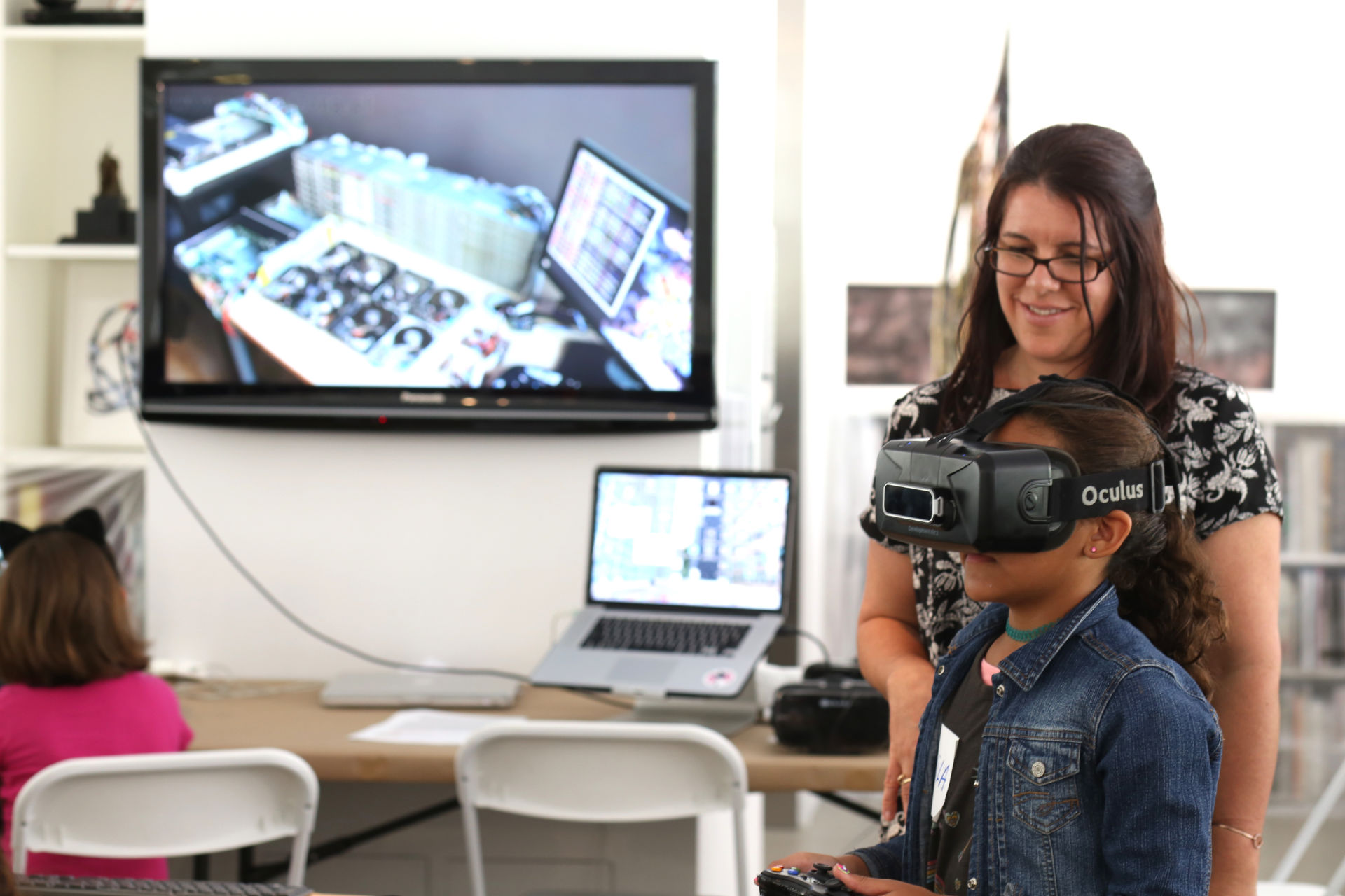 A kid using an Oculus and a woman smiling